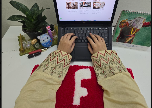 Person using a laptop with a custom keyboard rug on a workspace desk
